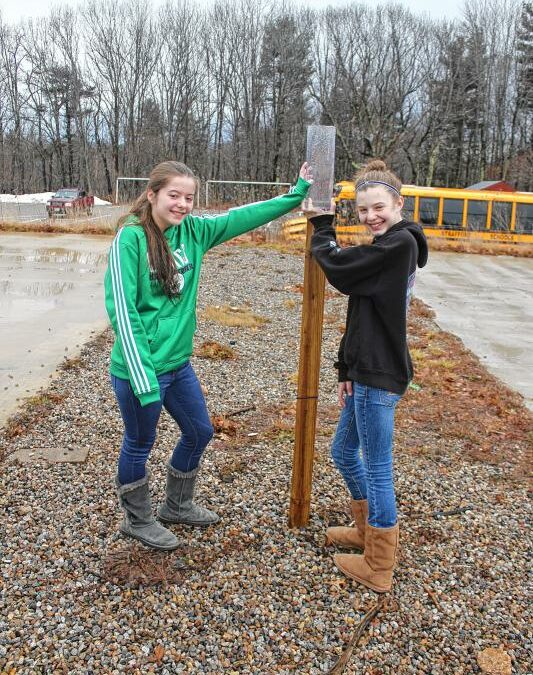 Strafford School 6th-graders Rylee Barry, left, and Elizabeth Marston pour at the CoCoRaHS rain gauge at their school. (Courtesy photo)