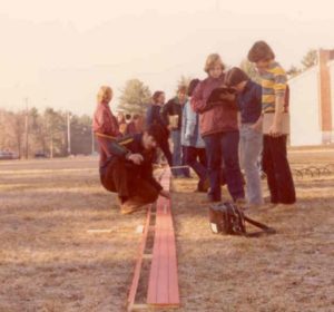 Pedro Perez kneels and checks the workings of a 320-foot-long slide rule in front of Alvirne High School on March 22, 1979.