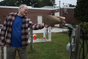 Former NHTI professor Thomas Hopper carefully checks an electric car-charging station that is used so seldom that it contains an active wasp’s nest.