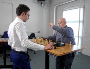 2016 photo: Michael Kind (right) CEO of Right Height Manufacturing, ponders a move in a speed-chess game against U.S. Chess Champion Fabiano Caruana at the company’s offices in the Manchester Millyard. They are playing on an adjustable-height Prodigy Desk.