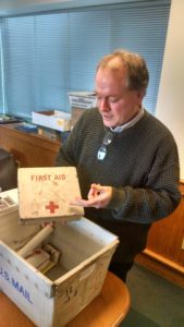 Aviation Museum Director Jeff Rapsis holds a First Aid kit from a DC3 that cdrashed on Mt. Success in 1954. Yes, that's blood on it.