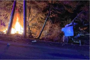 Courtesy photo by Michelle Barnhart: A Tesla X on fire after crashing into woods in Rindge on Dec. 26, 2018. One passenger died.