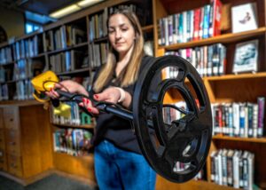 Ashley Miller, archivist, reference and outreach coordinator for the Concord Library, holds up a metal detector that is available for checkout at the library. Geoff Forester/ Monitor staff