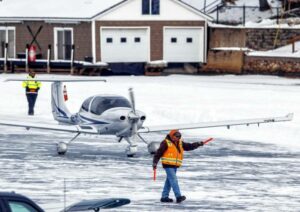 An aircraft official directs a plane on the ice at the Alton Bay airstrip on Sunday. The strip operates like any airport lacking a control tower. The ice on Lake Winnipesaukee must be at least a foot thick over a large area for landings. GEOFF FORESTER / Monitor staff
